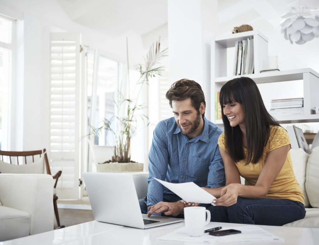 A Couple Looking At A Laptop In A White Room