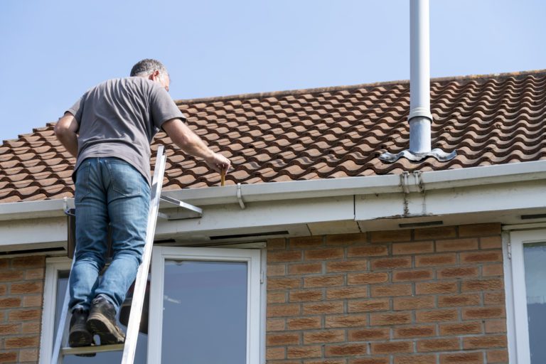 Man performing roof maintenance on his home.