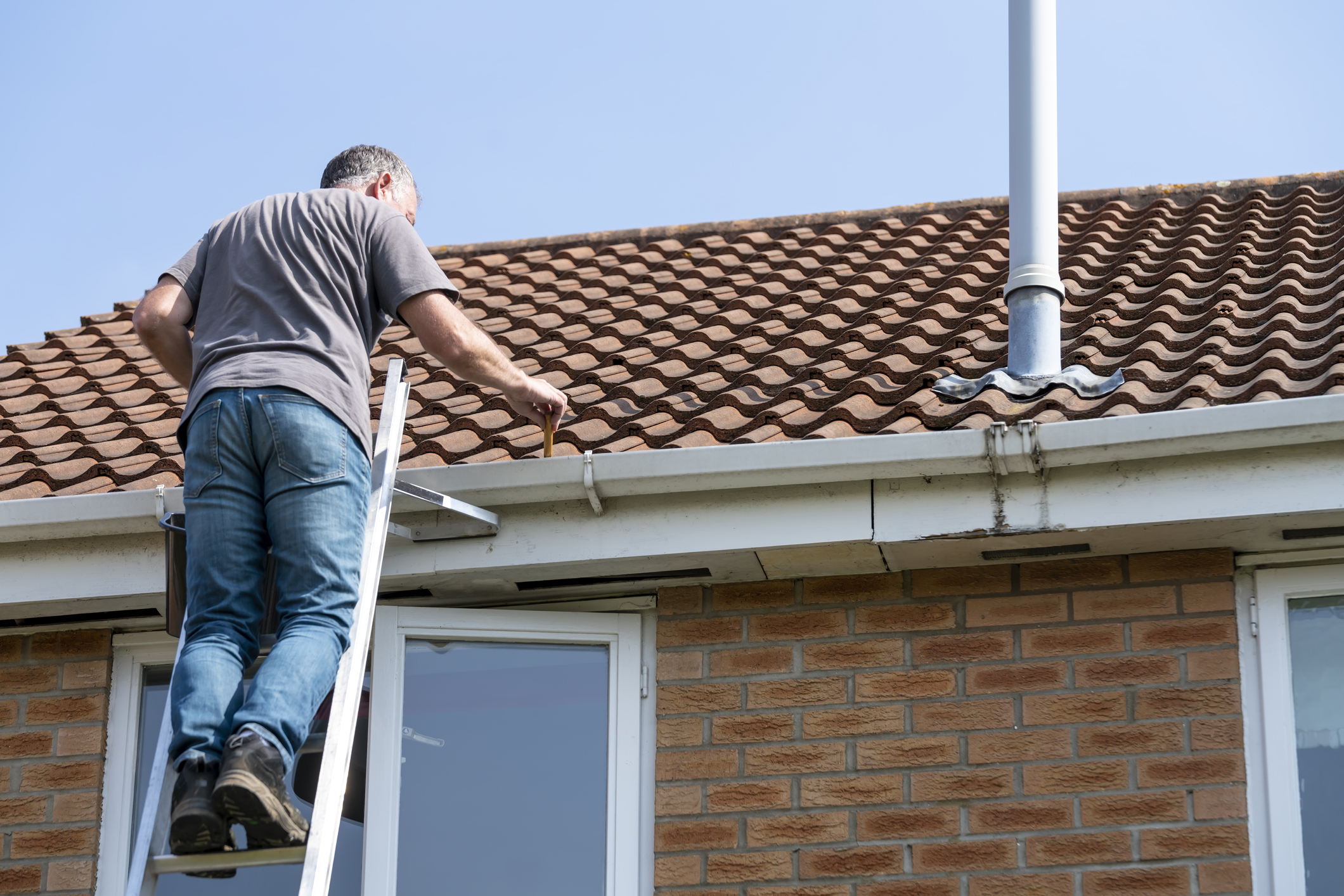 Expert Home Remodeling in Baldwin, NY - Unified Home Remodeling Man performing roof maintenance on his home.