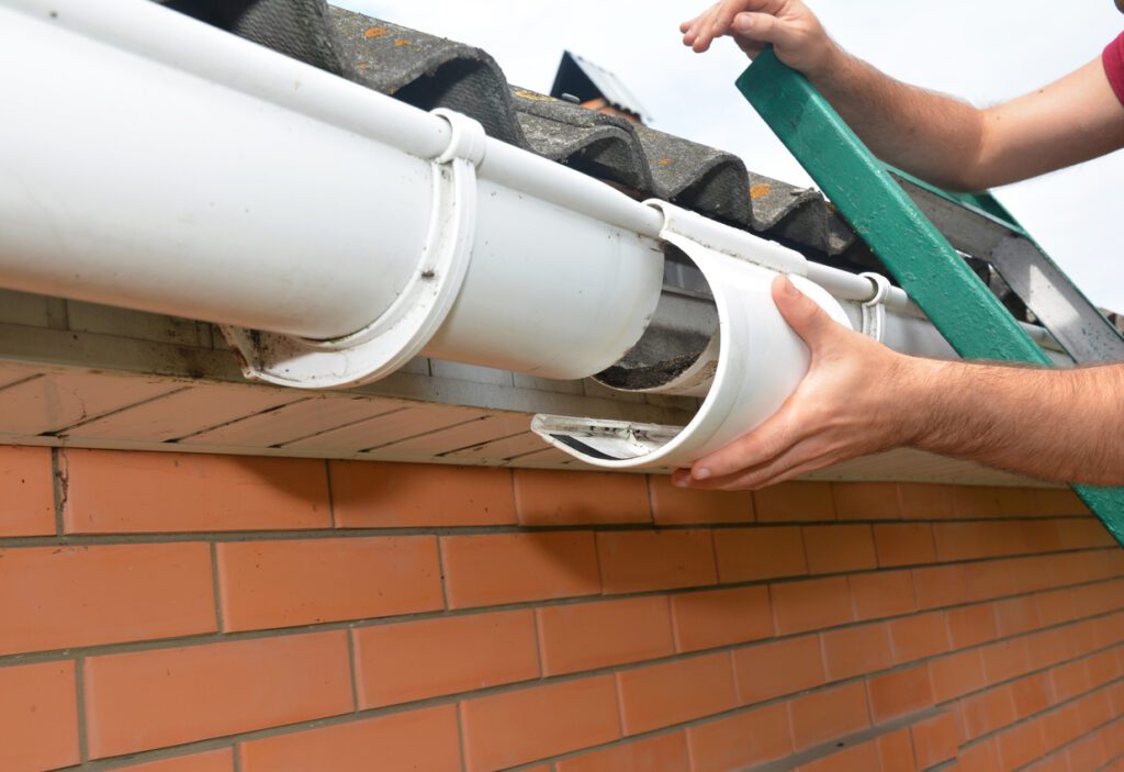Roof gutter installation. Guttering repair. Roofer contractor repair house rain gutter pipeline.