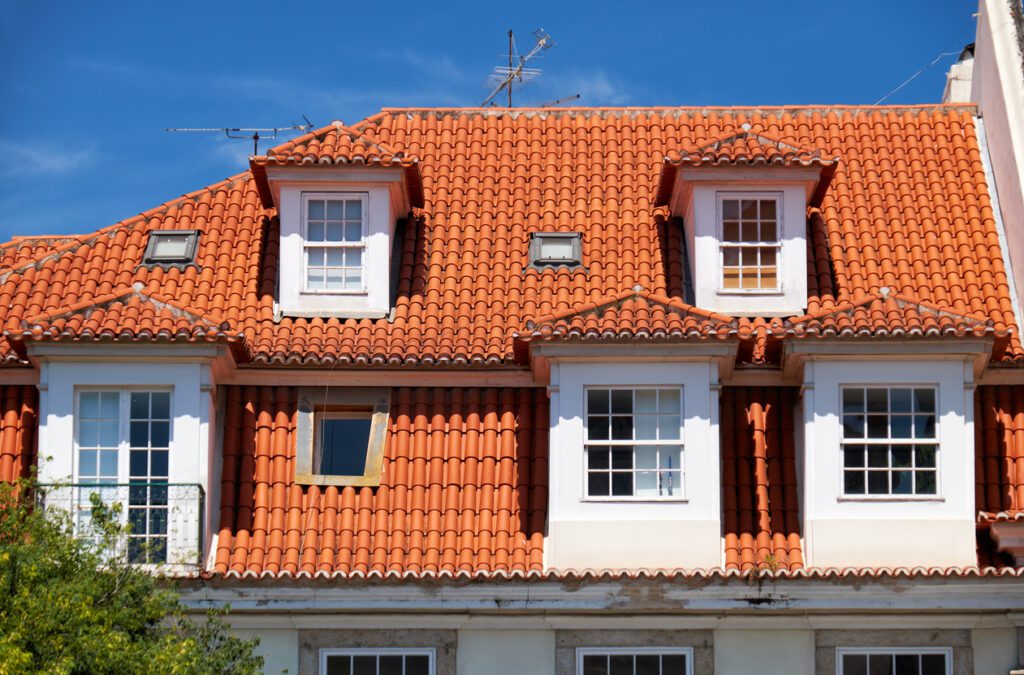 The view of mansard tiled roof with hip roof dormer windows in Lisbon. Portugal