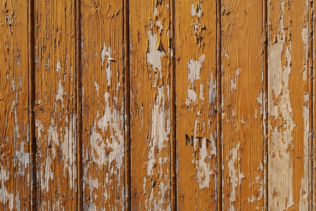 Vinyl or Wood Fence: Which One Is Best for Your Yard? - Unified Home Remodeling a peeling wood fence in need of maintenance