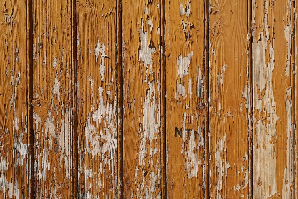 a peeling wood fence in need of maintenance