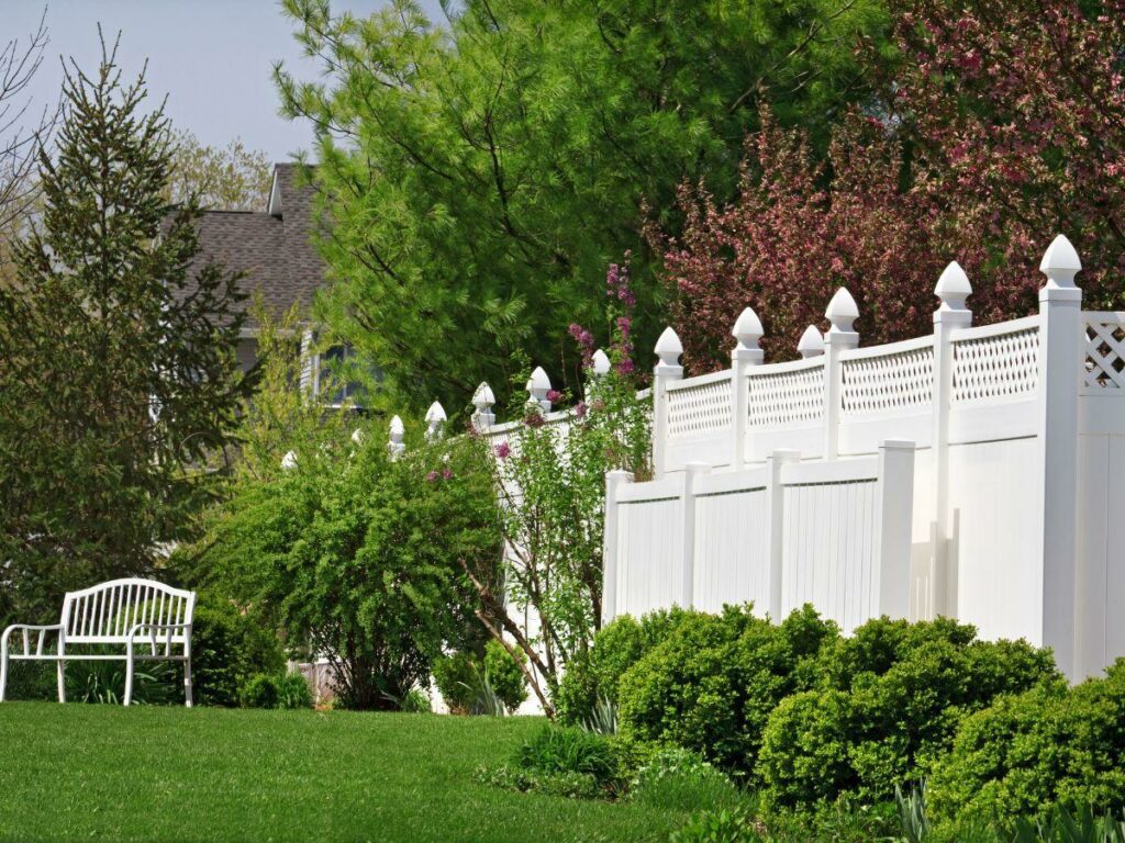 white vinyl fence overgrown with plants