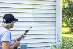 woman power washing siding on Long Island home