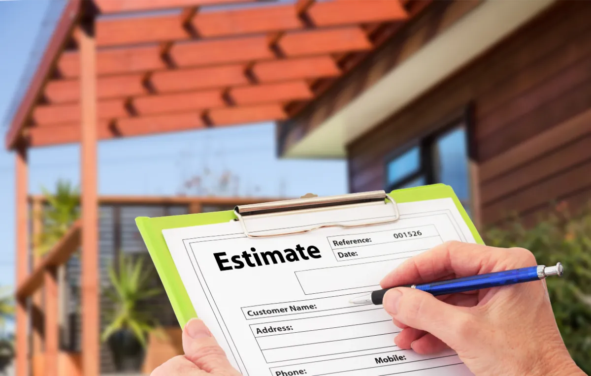 Hand holding a pen filling out a roofing estimate form in front of a Long Island home