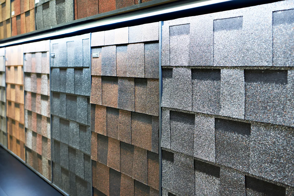 Close-up of asphalt roofing shingles in different colors and textures on display at a showroom.