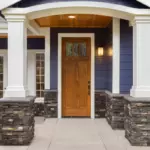 Mid-range wood entry door replacement on Long Island with covered porch and sidelights nearby