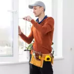 window installer adjusting replacement window frame inside a Long Island home