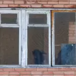 Old drafty wood window with peeling paint and damaged framing before window replacement in New York