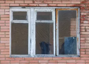 Old drafty wood window with peeling paint and damaged framing before window replacement in New York