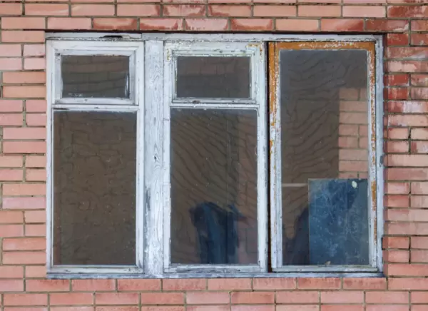 Old drafty wood window with peeling paint and damaged framing before window replacement in New York