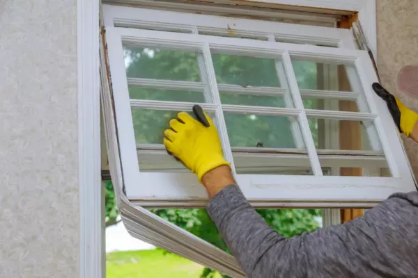 Contractor removing an old window during a replacement window project on Long Island