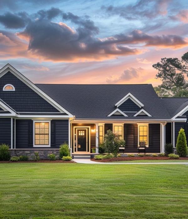 Modern single-story home with black siding, white trim, stone foundation, and covered front porch at sunset.